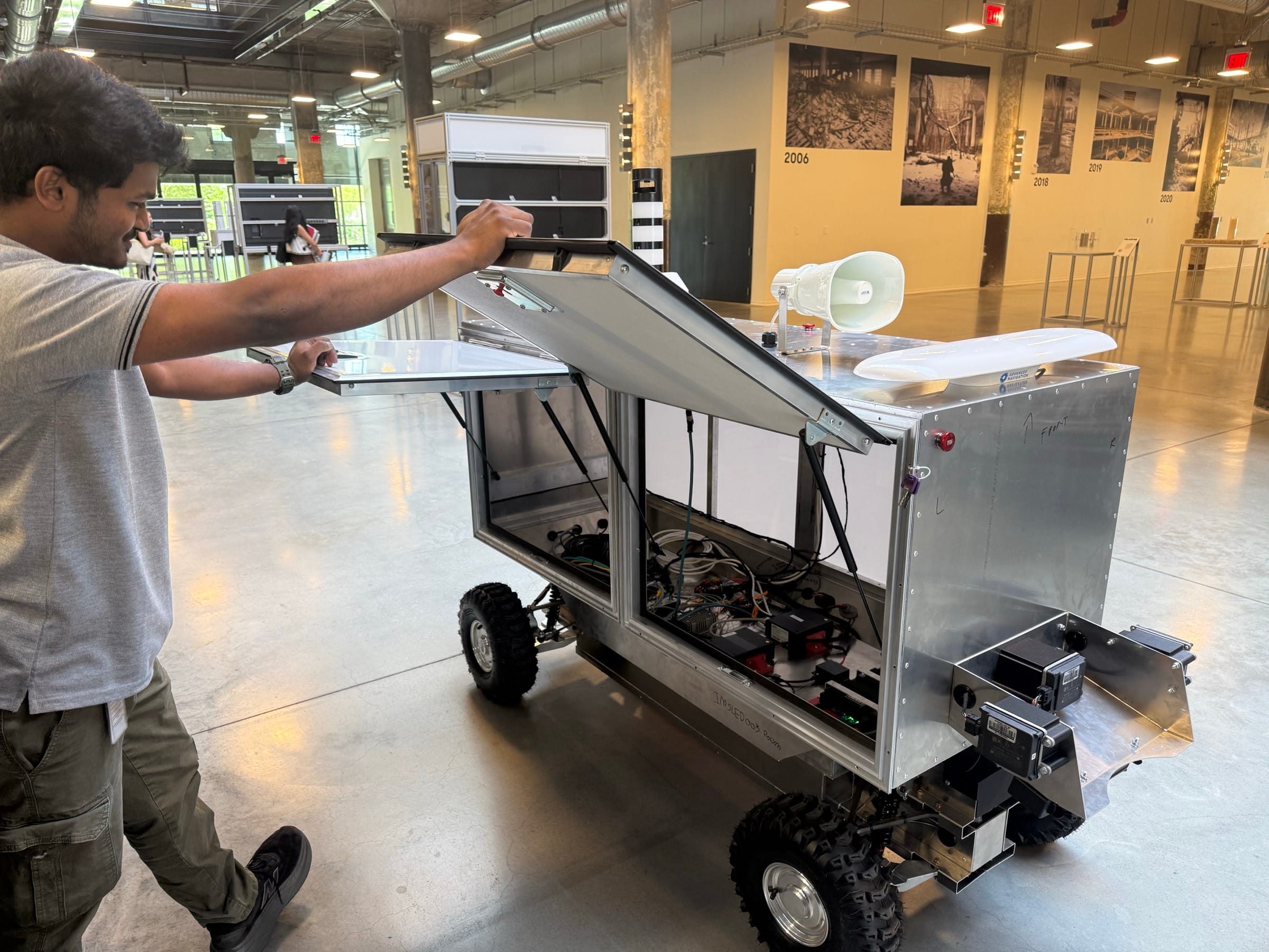 A CVR engineer opens the service panels on a prototype ground robot at Newlab Detroit